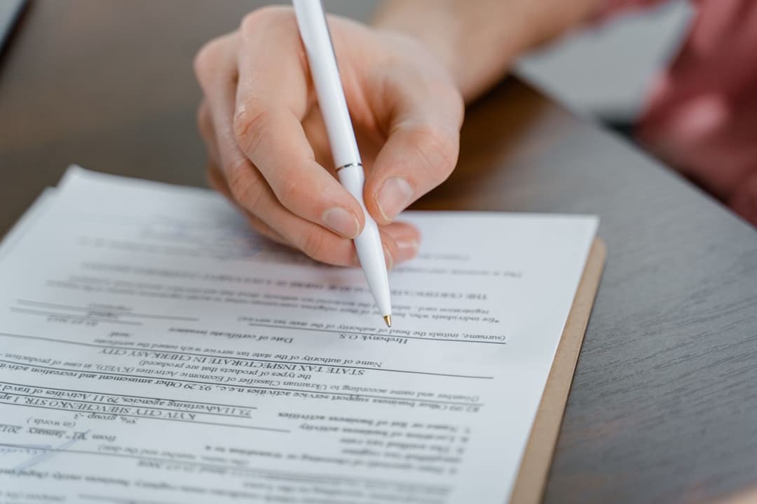 Signing a legal contract with a pen over printed agreement paperwork